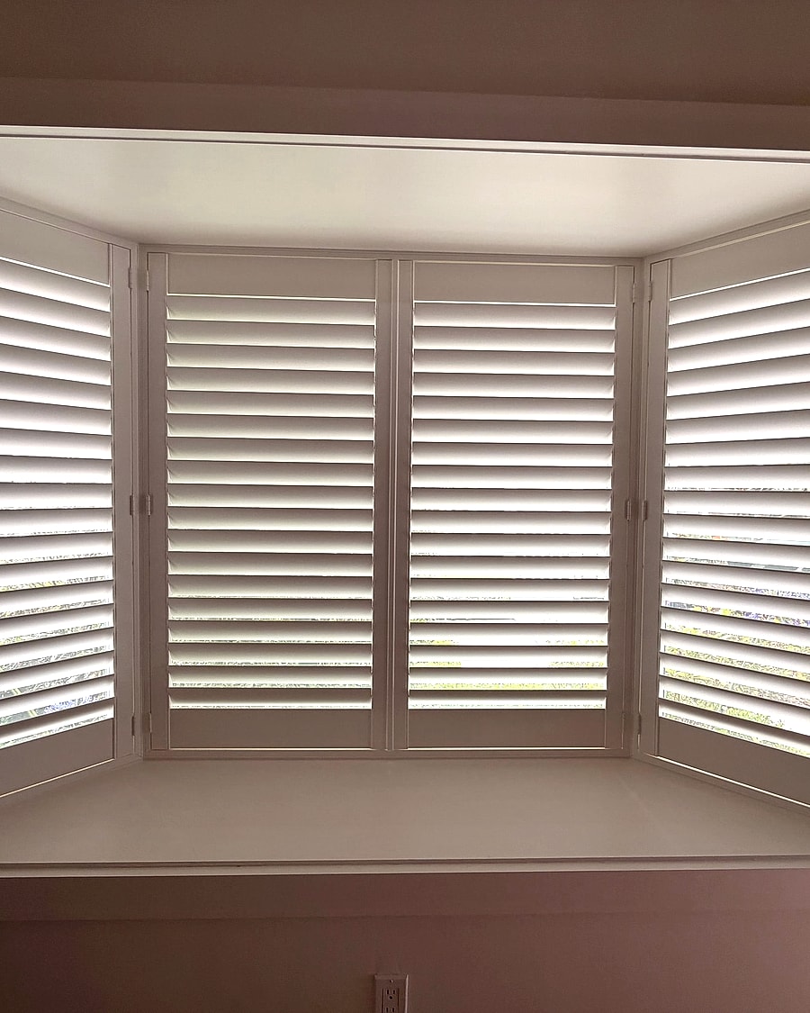 White plantation shutters installed across a Ventura County bay window
