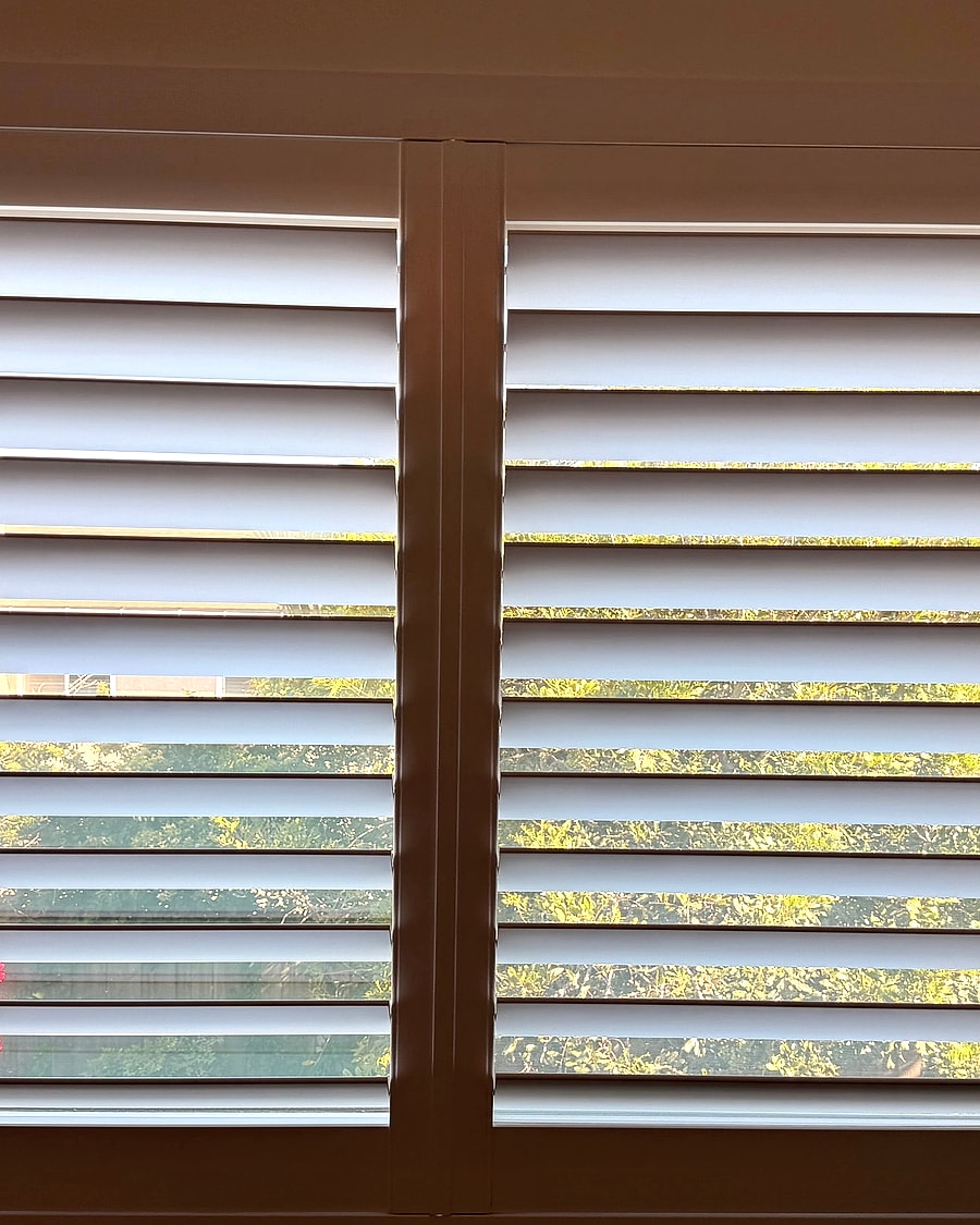 Straight-on view of white plantation shutters in a Ventura County bedroom