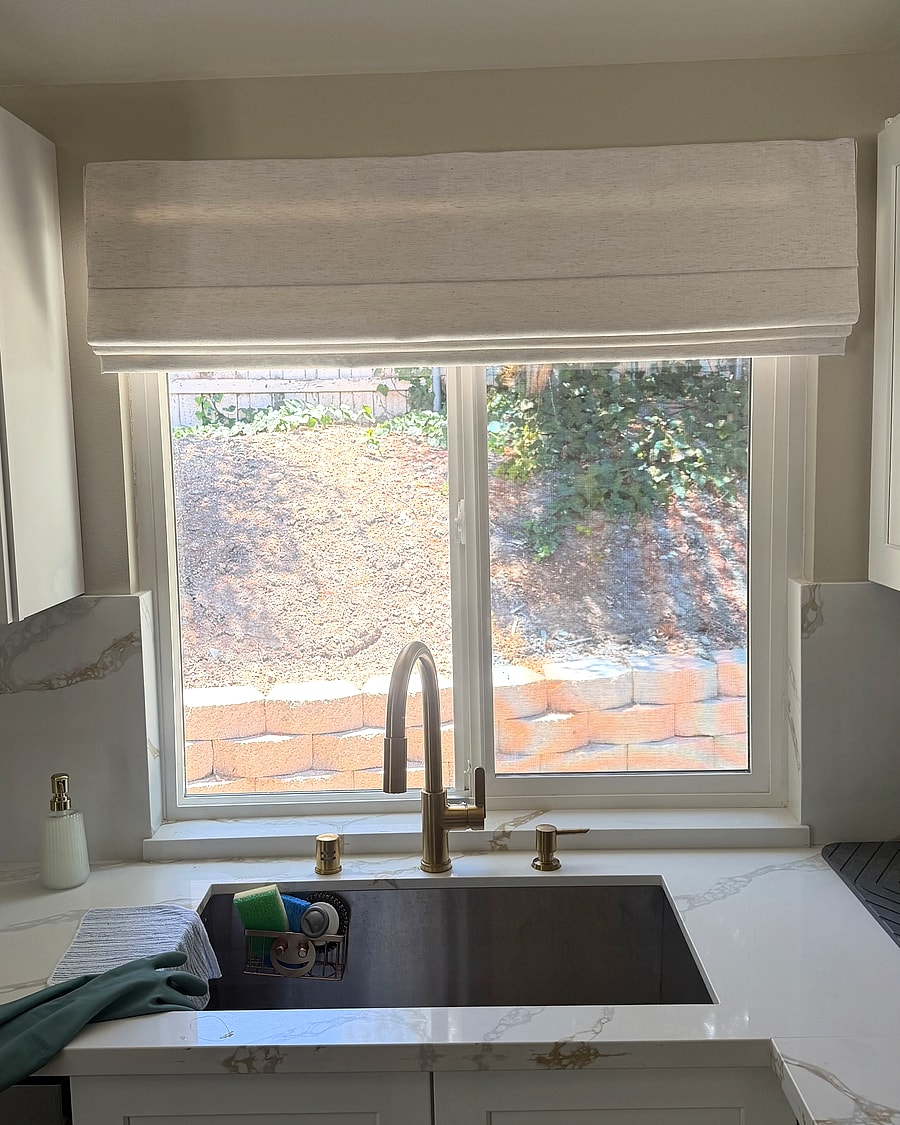 Textured Roman shade raised above a Ventura County kitchen sink window