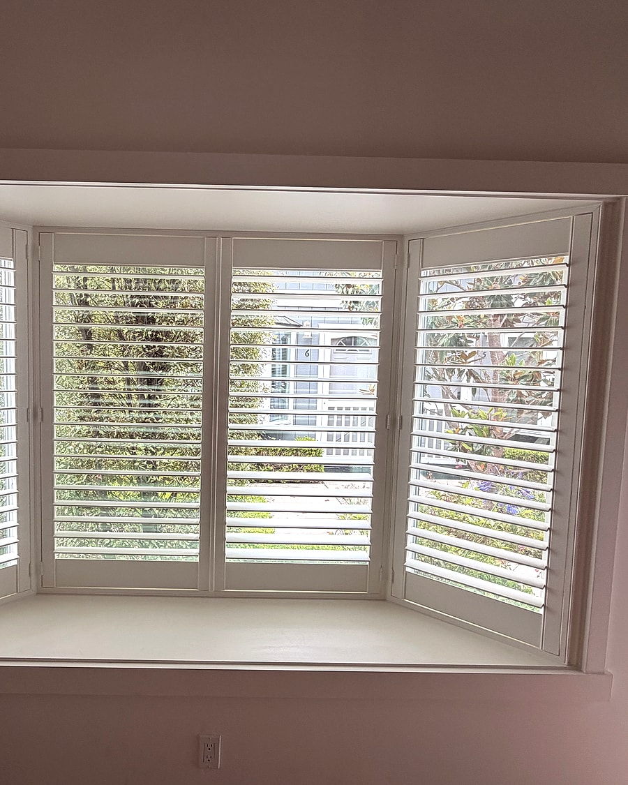 White plantation shutters installed across a bay window