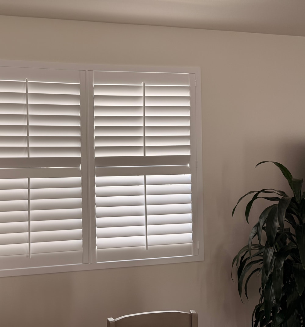 Close view of white split tilt plantation shutters with independently controlled louvers