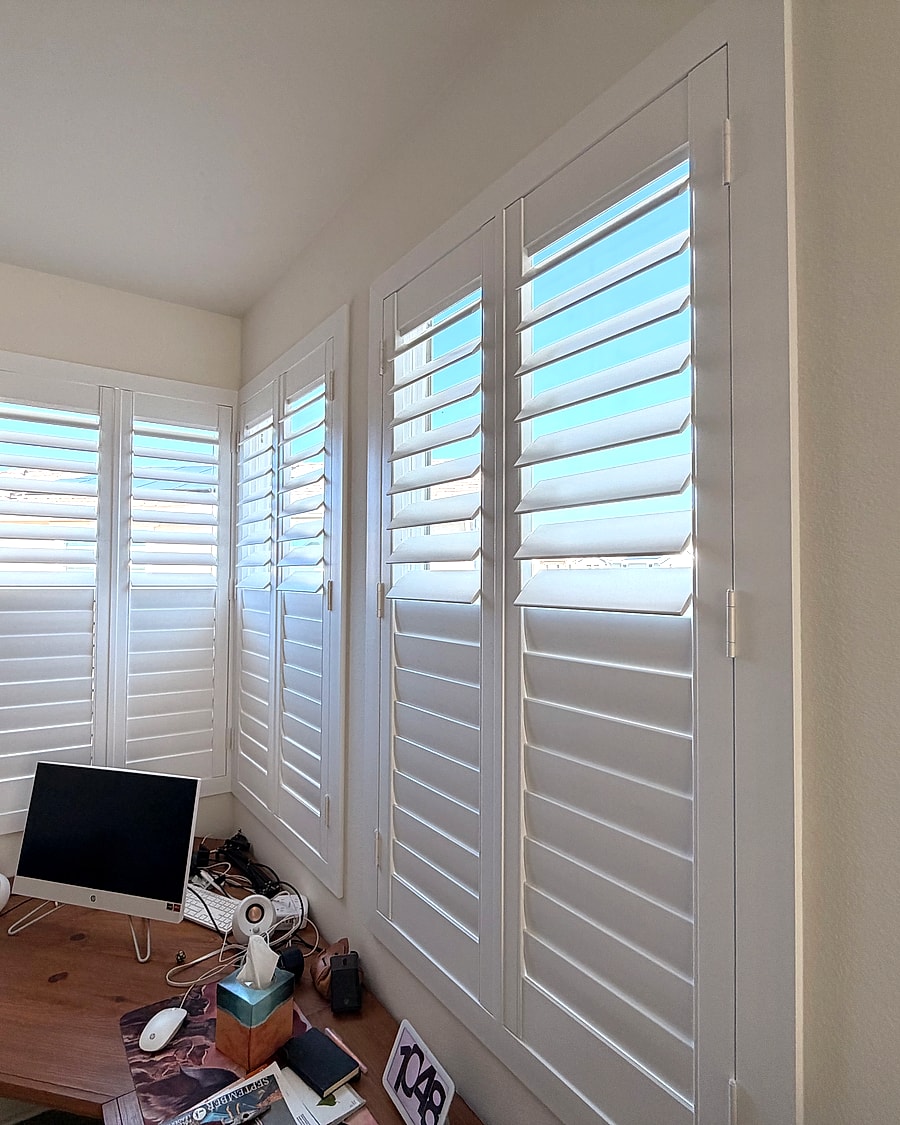 White plantation shutters installed over office corner windows