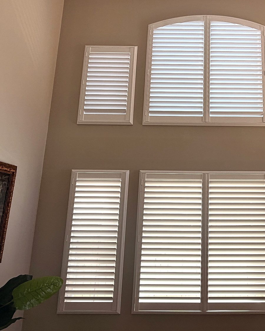 Stacked arched and rectangular shutters installed on tall living room windows